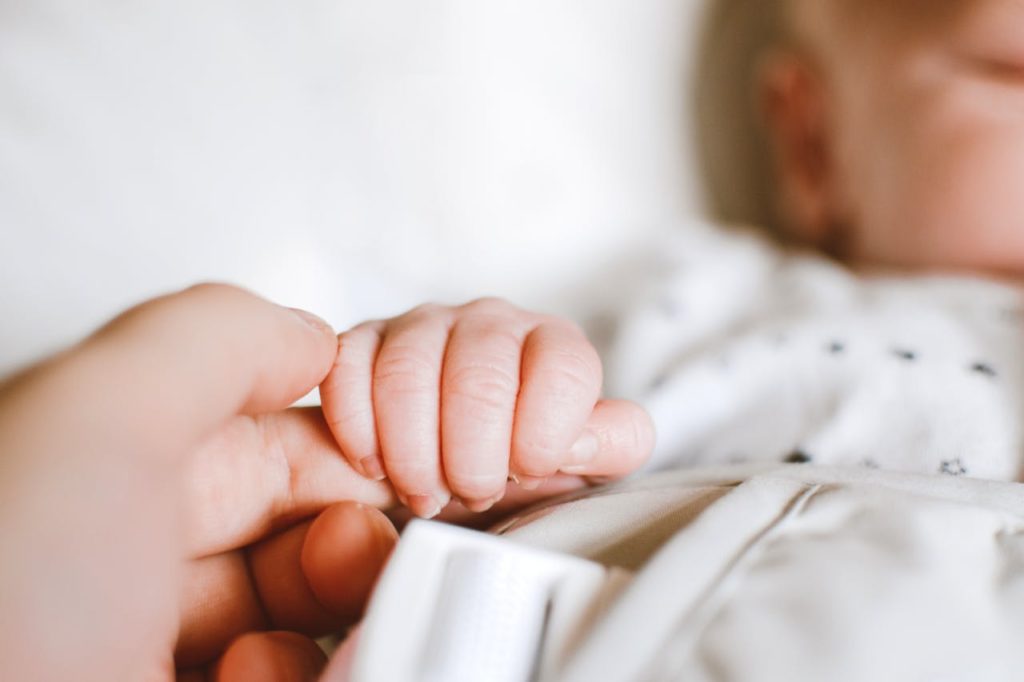 Close-up of a newborn's hand gently gripping a parent's finger, symbolizing love and connection.